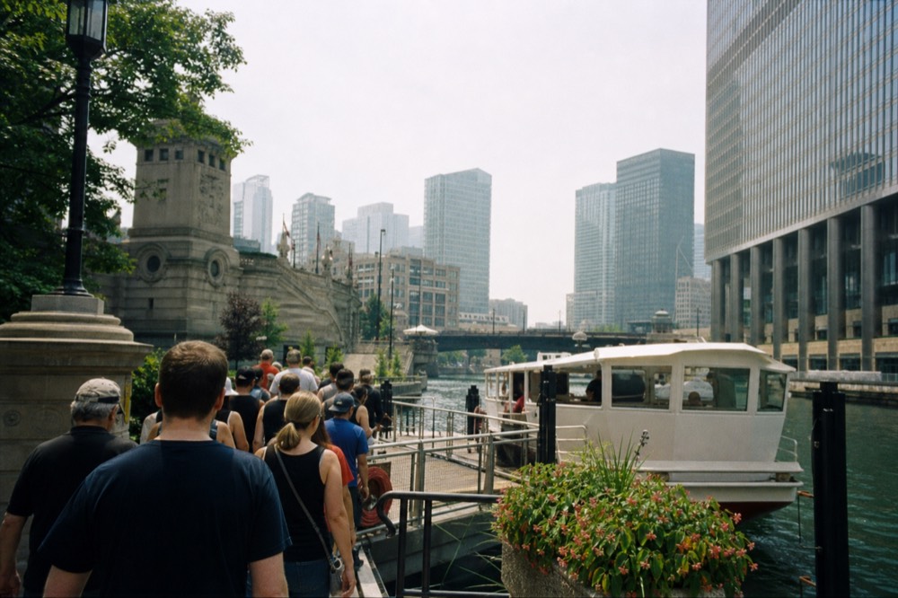 Passengers boarding a river cruise boat at a Riverwalk dock, no text, no logos, no people.