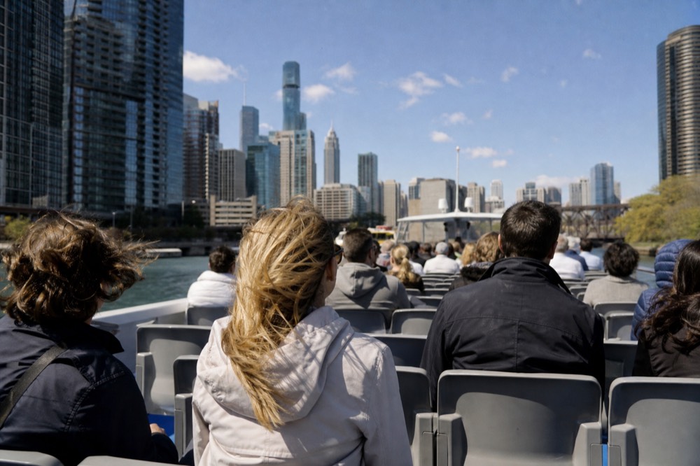 Open tour boat cruising the Chicago River between tall buildings on a bright day, no text, no logos, no people